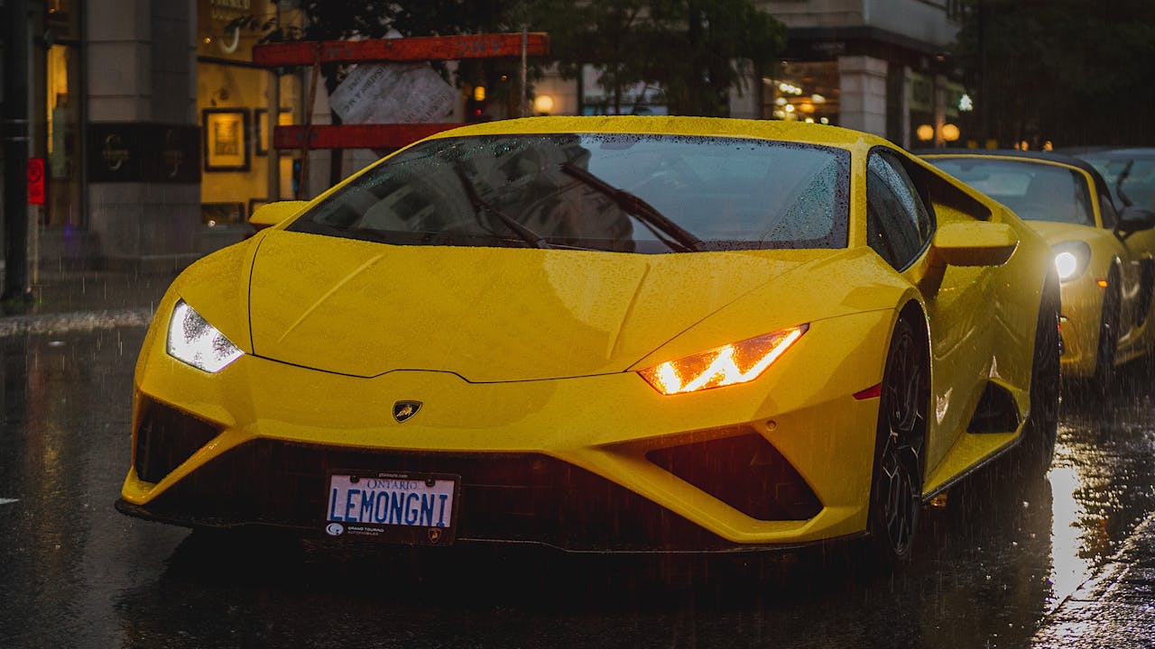 Vibrant yellow Lamborghini in urban setting during rain, capturing luxury and speed.